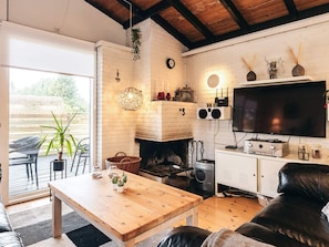 A cozy living room with a fireplace, a television, and a dining area. - Spacious Holiday Home in Væggerløse near Sea (Vaeggerlose)