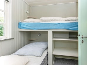 A bunk bed room with a window, a door, and a shelf.