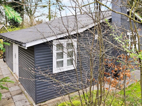 A small, dark-colored wooden building with a sloped roof and a single window.