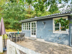 A small house with a patio, a table with chairs, and a number '37' on the door.