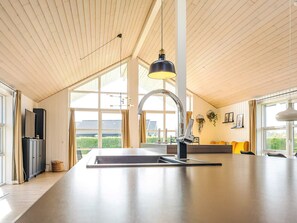 A modern kitchen with a large island, a hanging pendant light, and a view of the outdoors. - 5 Star Holiday Home in Hadsund (Hadsund)