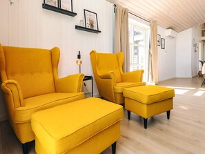 A bright yellow armchair and ottoman set in a room with white walls and wooden flooring. - 5 Star Holiday Home in Hadsund (Hadsund)
