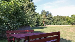 A wooden bench and table in a grassy area with trees in the background. - 12 Person Holiday Home in Laeso-by Traum (Læsø)