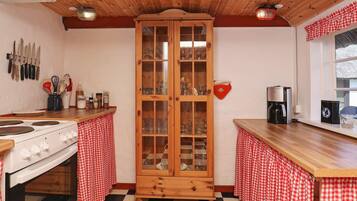 Uma cozinha com piso xadrez, armários de madeira, fogão e cafeteira.