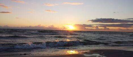 A beach with waves and a sunset.