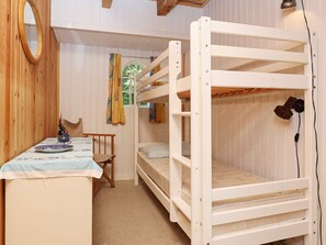 Habitación con literas, una mesa, una silla, un espejo y una ventana con cortinas.