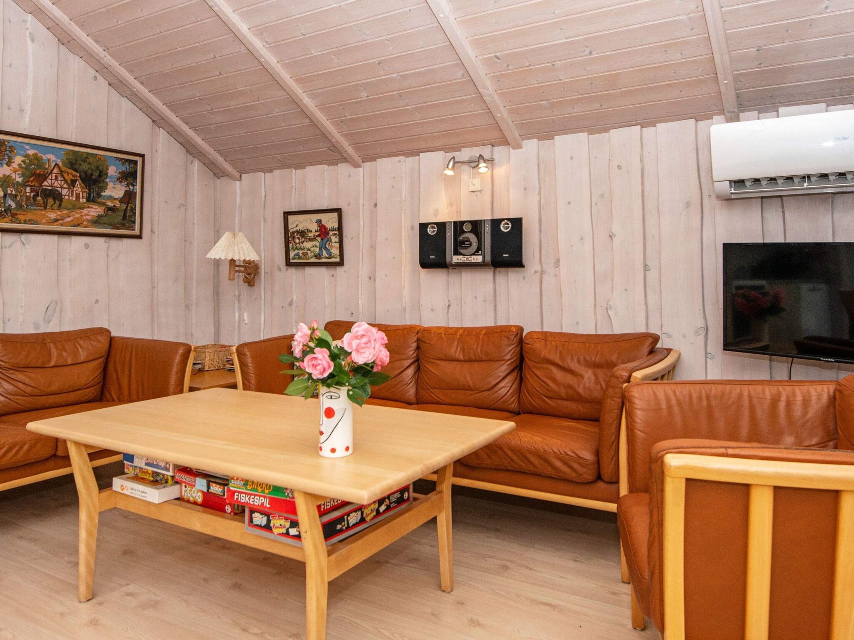 A cozy living room with a wooden table, leather sofa, and a television.
