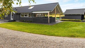 A modern house with a covered patio, a fenced yard, and a gravel driveway. - 4 Star Holiday Home in Hovborg (Hovborg)