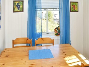 A dining room with a wooden table, chairs, a blue table runner, and a window with blue curtains. - 4 Star Holiday Home in Oksvoll (Orland)