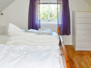 A bedroom with a bed, a window with curtains, a dresser, and a clock on the wall. - 4 Star Holiday Home in Oksvoll (Orland)