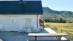 A white building with a dark roof, a chimney, and a deck with chairs and a table. - 4 Star Holiday Home in Oksvoll (Orland)