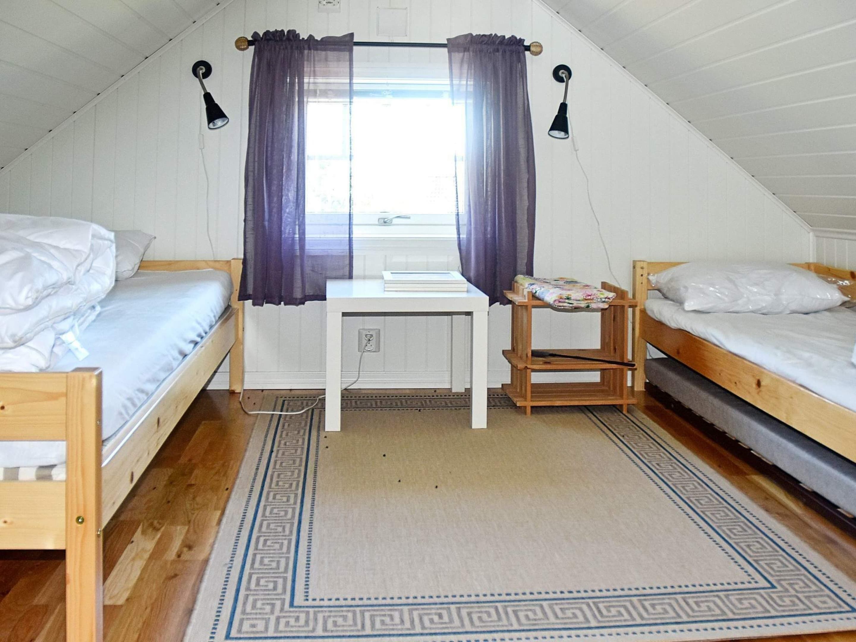 Una habitación tipo dormitorio con dos camas, un escritorio, una silla y una ventana con cortinas.