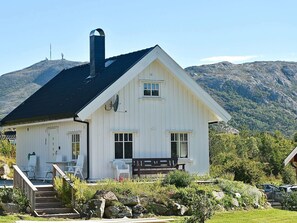 A white house with a black roof, a chimney, and a deck with chairs. - 4 Star Holiday Home in Oksvoll (Orland)