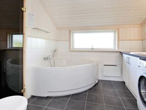 Ein modernes Badezimmer mit freistehender Badewanne, Toilette und Waschmaschine.