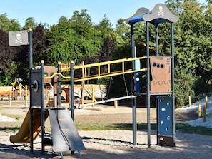 A playground with a slide, monkey bars, and a pirate-themed play structure.