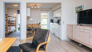 Moderni, avoimen pohjaratkaisun mukainen olohuone, jossa on ruokailutila, keittiö ja televisio.