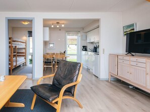A modern, open-plan living space with a dining area, a kitchen, and a TV. - 6 Person Holiday Home in Romo (Rømø)