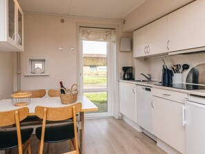 A modern kitchen with white cabinets, a coffee maker, and a view of the outdoors. - 6 Person Holiday Home in Romo (Rømø)
