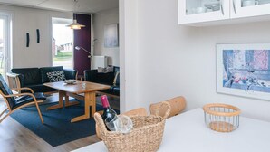En moderne stue med sofa, stole, spisebord og et køkken med skabe.