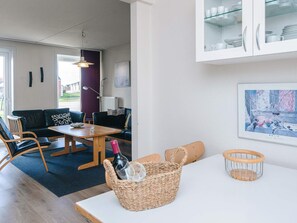 A modern living room with a sofa, chairs, a dining table, and a kitchen area with cabinets.