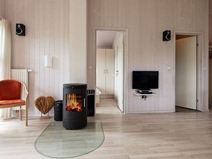 A modern living room with a wood-burning stove, a television, and a red chair.