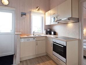 Una cocina compacta equipada con lavavajillas, horno, microondas y cafetera.