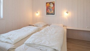 Une chambre avec deux lits, des murs en bois, un tableau et des lampes fixées au mur.
