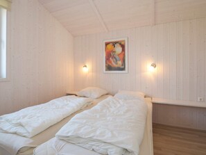 A room with two beds, wooden walls, a painting, and wall-mounted lights. - Holiday Home in GrÃ¶mmitz (Groemitz)