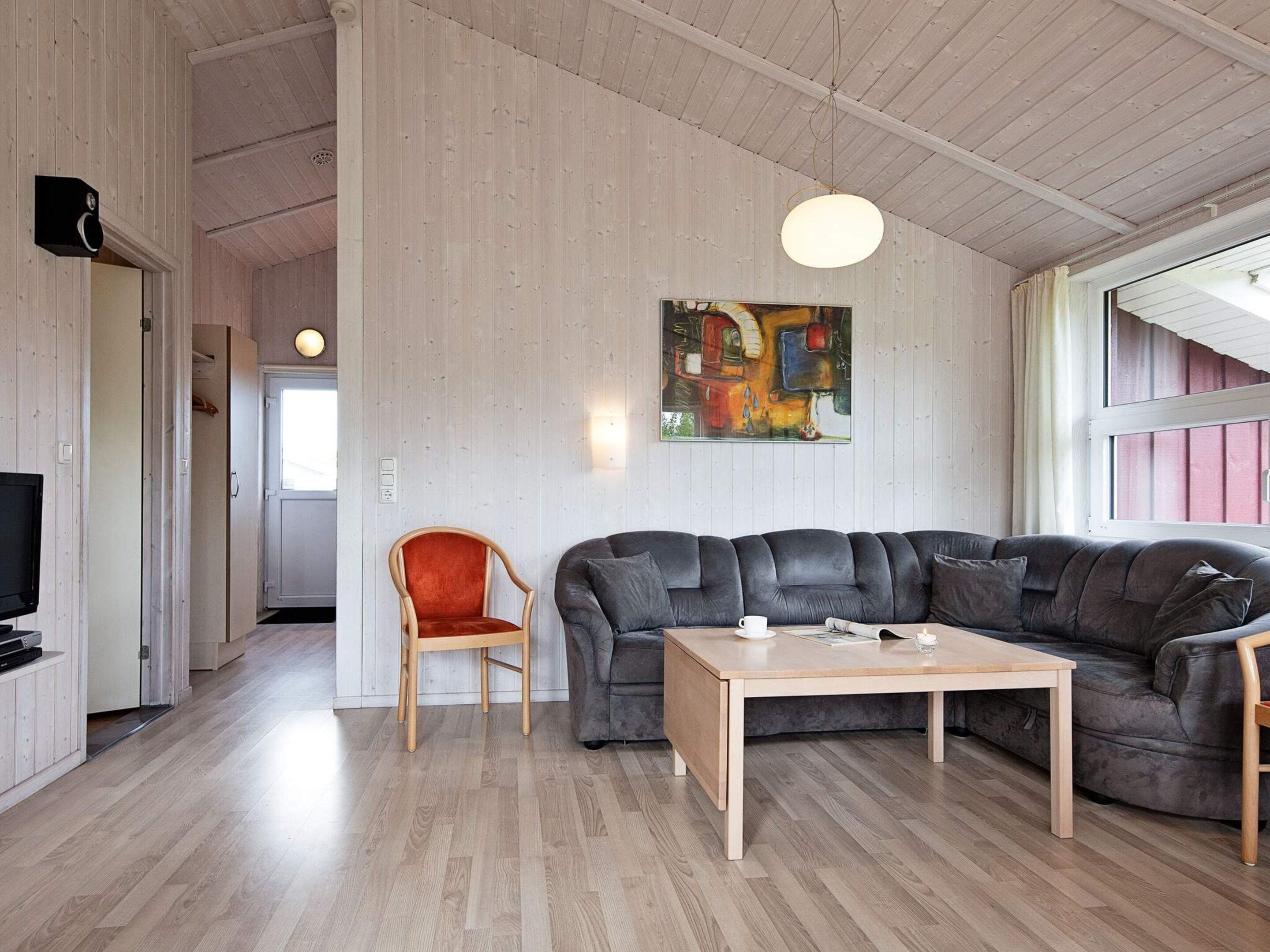 Un salon moderne avec un canapé d’angle, une table basse en bois et un fauteuil.