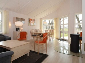 A modern living room with a dining area, large windows, and a glass coffee table.