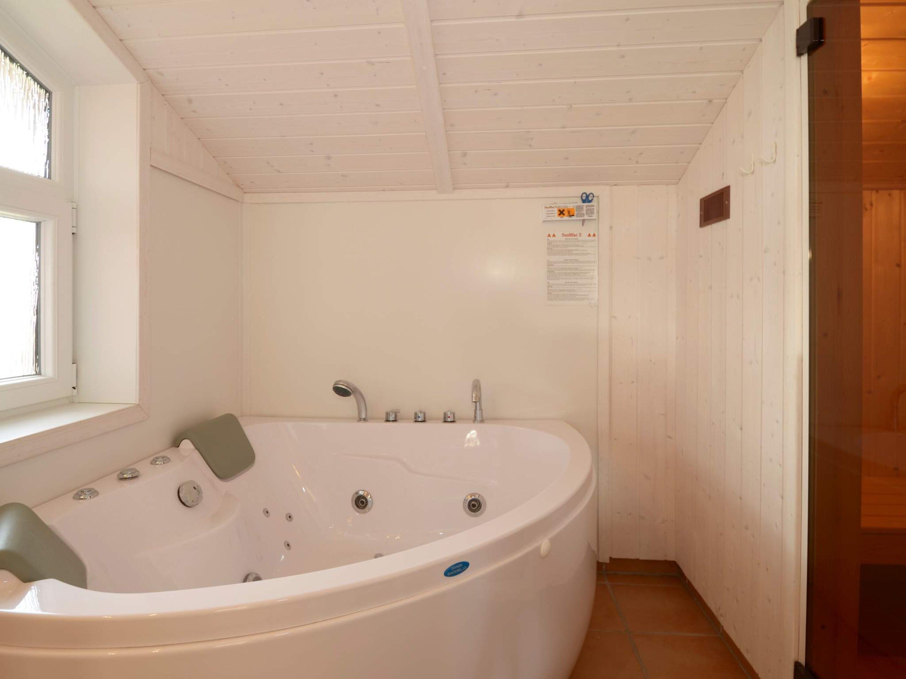 Ein Badezimmer mit einer freistehenden Badewanne, einem Fenster und einer Holztür.
