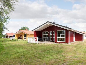 A red building with a covered porch and a white fence. - Holiday Home in GrÃ¶mmitz (Groemitz)
