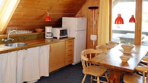 Ett mysigt kök med träskåp, ett vitt kylskåp, en kaffebryggare och ett matbord med stolar.