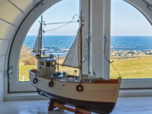 Enjoy the serene view of the sea and rocky shoreline from this room's large arched window.