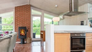 Une cuisine moderne dotée d’un four encastré, d’une cheminée en briques et d’une grande fenêtre donnant sur un jardin.