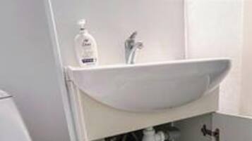 A bathroom with a white sink, a mirror, and a bottle of hand soap.