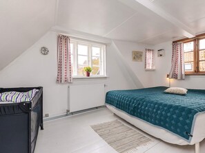 A bedroom with a bed, a radiator, a window with curtains, and a small plant. - 4 Person Holiday Home in Aeroskobing (Aeroskobing)