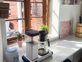 Una cocina con cafetera, una planta en maceta y un mueble rosa.