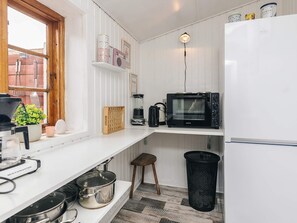 Ett kompakt kök med mikrovågsugn, kaffebryggare och en liten pall.