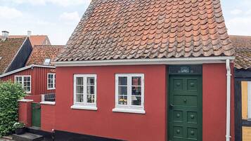 A red building with a green door, white windows, and a tiled roof.