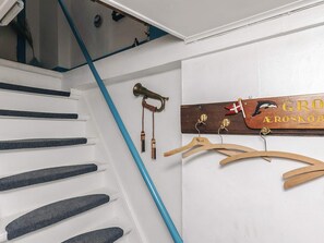 A staircase with a blue accent, a wooden sign with a flag, and wooden hangers. - 4 Person Holiday Home in Aeroskobing (Aeroskobing)