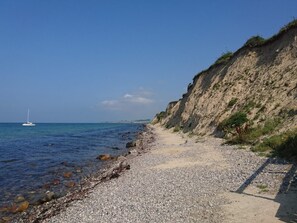 A coastal path with pebbles, a sandy beach, and a cliff. - 4 Person Holiday Home in Aeroskobing (Aeroskobing)