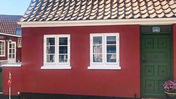 A red building with two white-framed windows and a green door.