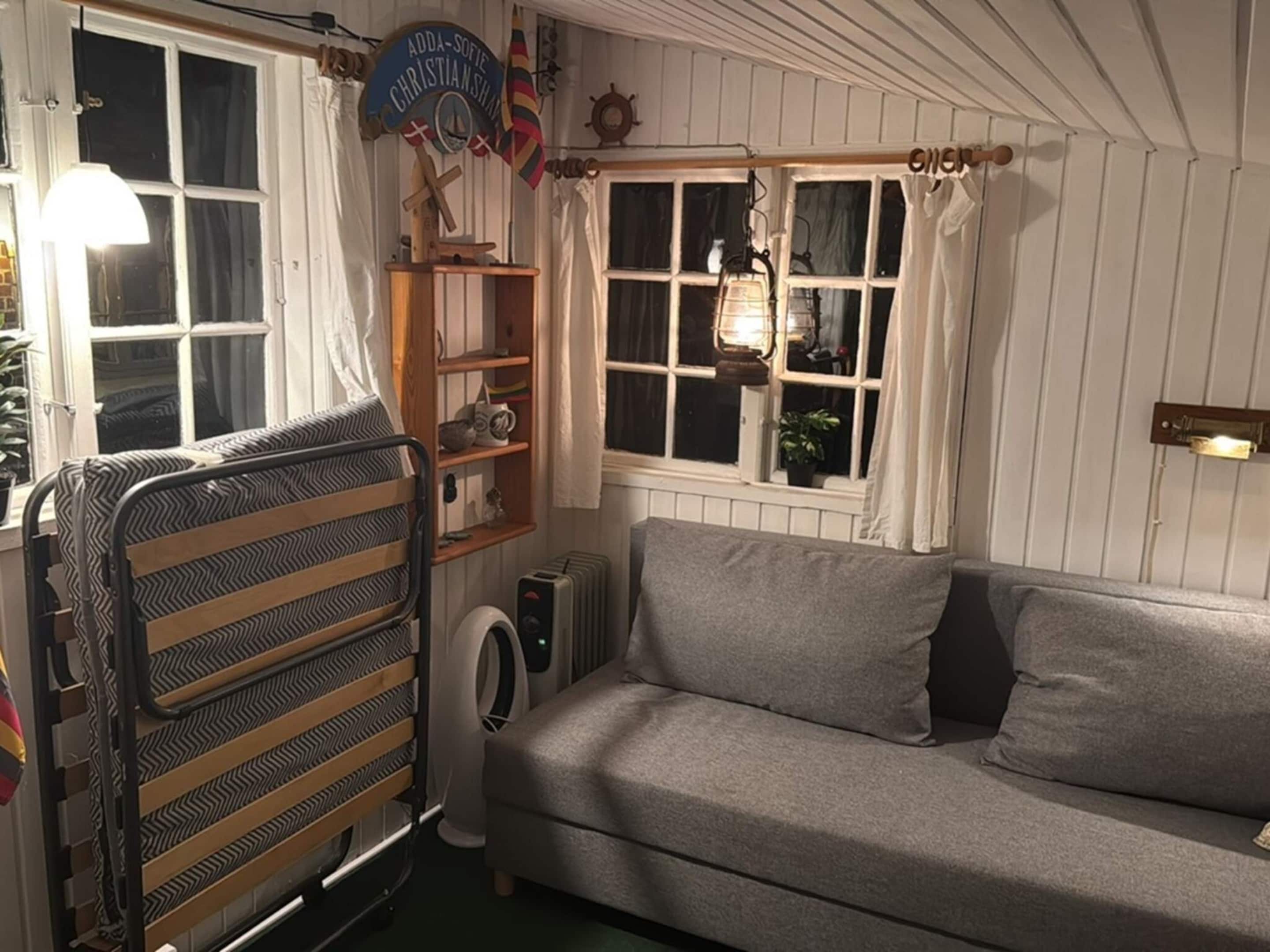 Ein gemütliches Zimmer mit Etagenbett, einer Couch, einem Heizkörper und einem Fenster mit Vorhängen.