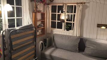 Ein gemütliches Zimmer mit Etagenbett, einer Couch, einem Heizkörper und einem Fenster mit Vorhängen.