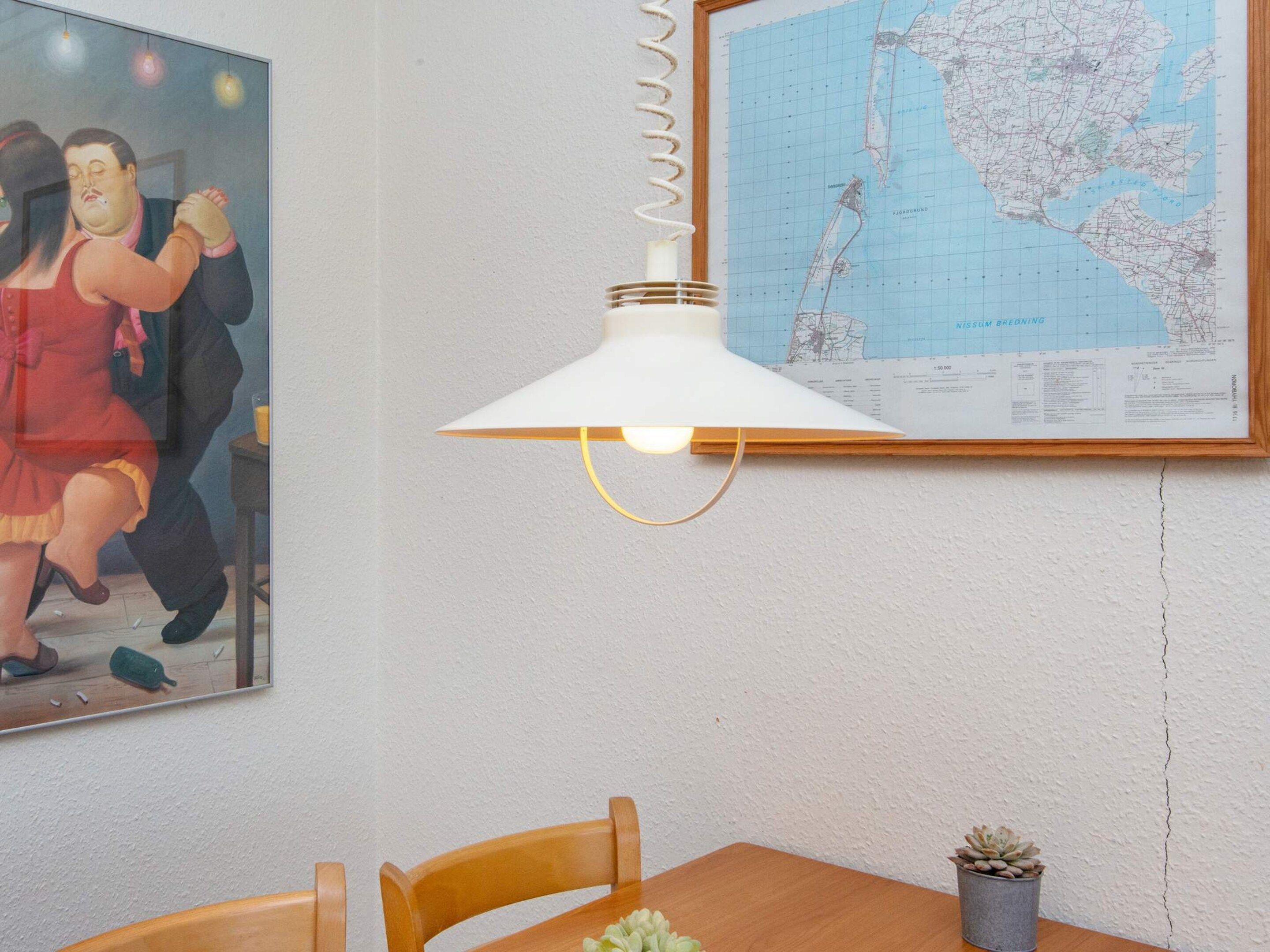 A dining area with a table, chairs, a map on the wall, and a hanging lamp.