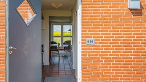 Una porta che dà su una stanza con pavimento piastrellato, un tavolino e una sedia.
