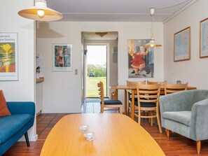 A dining area with a wooden table, chairs, and a view of the outdoors. - Cozy Holiday Home in Jutland near Sea (Lemvig)