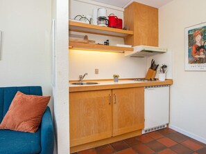 A compact kitchenette with a sink, wooden cabinets, and a countertop. - Cozy Holiday Home in Jutland near Sea (Lemvig)