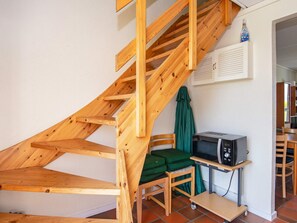 A wooden staircase leading to an upper floor, a microwave on a small table, and a green chair. - Cozy Holiday Home in Jutland near Sea (Lemvig)
